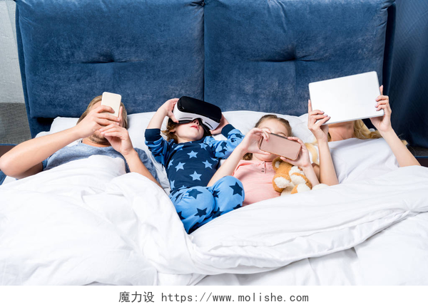 一家人躺在床上玩电子产品家庭与躺在床上的小工具